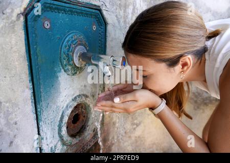 Primo piano della giovane donna si idrata da una fontana durante un'onda di calore in città Foto Stock