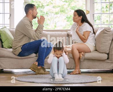 Non riesce più ad ascoltare. Shot di una bambina che copre le sue orecchie, mentre i suoi genitori discutono a casa. Foto Stock