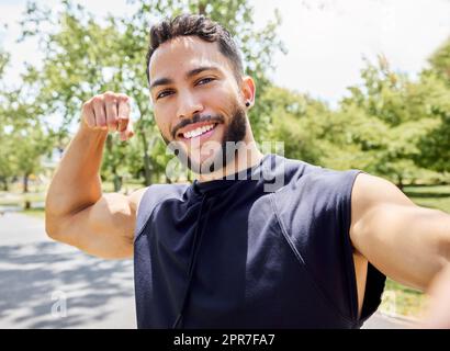 Bicipite non crescono sugli alberi. Ritratto di un giovane sportivo che flette il bicipite e prende selfie mentre si esercita all'aperto. Foto Stock