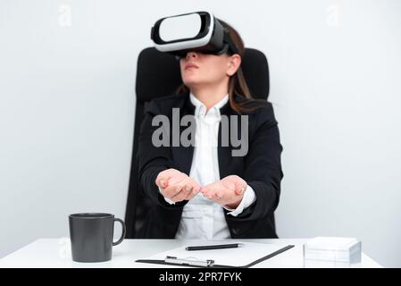 Gesturing di una donna dirigente mentre apprendi le competenze professionali tramite il simulatore di realtà virtuale. Donna che indossa un abito seduto alla scrivania e sperimenta la tecnologia moderna. Foto Stock