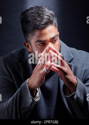 Aspetto dapper come sempre. Studio girato di un bel giovane uomo alla moda che si posa su uno sfondo scuro. Foto Stock