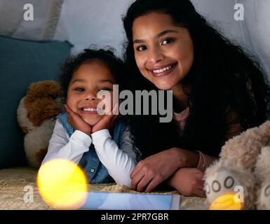 Amo quelli che più amavo per primi. Scatto di una bambina e di sua madre che guarda qualcosa su un tablet digitale di notte. Foto Stock