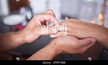 Una mano come la vostra ha bisogno di un anello grazioso. Un uomo irriconoscibile che mette un anello sul dito della sua ragazza a casa. Foto Stock