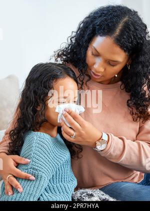 Una madre sarà lì per prendersi cura di voi, una giovane madre che aiuta sua figlia a soffiare il naso a casa. Foto Stock