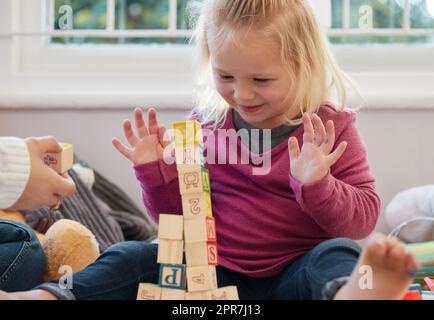 L'ho fatto. Una bambina accatastando blocchi con sua madre a casa. Foto Stock