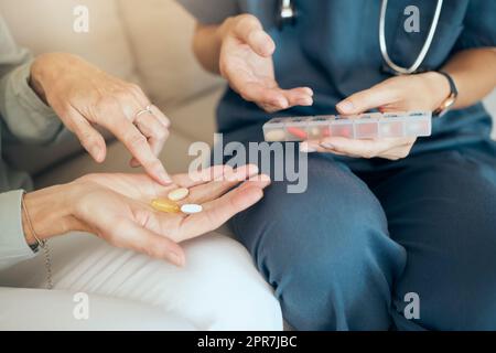 Primo piano con un medico irriconoscibile che offre supporto al paziente durante il recupero. Un medico amorevole e sconosciuto che tiene in mano farmaci e spiega il dosaggio al suo paziente Foto Stock