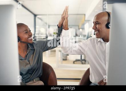 Due agenti di telemarketing soddisfatti del call center che si scambiano cinque premi e che fanno il tifo per la gioia mentre lavorano in ufficio. Consulenti entusiasti e ambiziosi che celebrano gli obiettivi di vendita di successo e la vittoria vincente Foto Stock