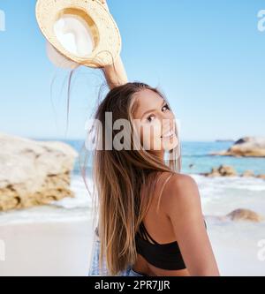 Una bella giovane donna caucasica che si rilassa sulla spiaggia. Godetevi una vacanza estiva o una vacanza all'aria aperta durante l'estate. Prendersi una pausa e allontanarsi da tutto. Passare la giornata da sola fuori Foto Stock