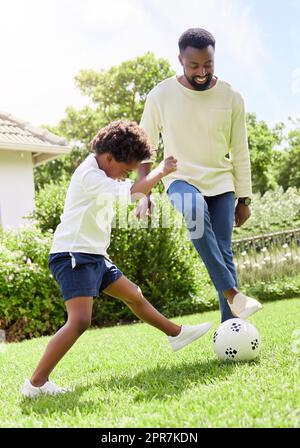 HES affronta il papà per la palla, un padre e un figlio che giocano a calcio all'aperto. Foto Stock