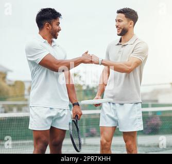 Due giocatori di tennis etnici sorridenti che danno pugno con pugno prima di giocare a una partita sul campo. Metti in piedi la squadra degli atleti e usa il gesto della mano per la buona fortuna. Gioca una partita sportiva competitiva per il fitness Foto Stock