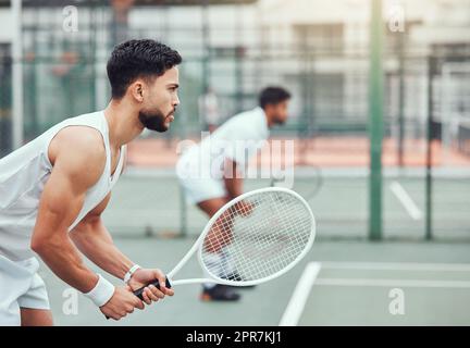 Due giocatori di tennis etnici con racchette e pronti a giocare in campo. Atleti seri e concentrati insieme in una posizione. Giocare a doppio competitivo partita come squadra per rimanere in forma e in salute nel club sportivo Foto Stock