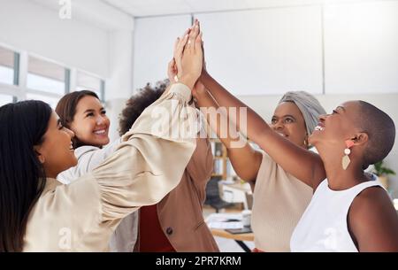 Gruppo eterogeneo di donne d'affari etniche sorridenti che ne danno cinque dopo una riunione di brainstorming in ufficio. Team di colleghi ambiziosi felici sicuri di sé che festeggiano un successo e si sentono entusiasti Foto Stock