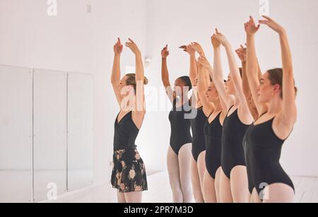 Giovane insegnante di danza che insegna una lezione di balletto a un gruppo di bambini nel suo studio. Insegnante di ballerina che lavora con studentesse, si prepara per il recital, l'esibizione o il prossimo spettacolo Foto Stock