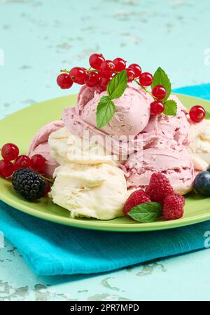 Misurini per gelato alla vaniglia e al lampone su un piatto rotondo verde Foto Stock