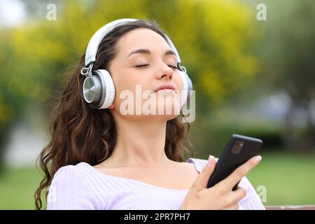 Donna che ascolta la guida in meditazione in un parco Foto Stock