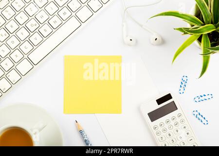 Annunci importanti su pezzi di carta su scrivania con fiori, cuffie, penna, calcolatrice, bevande calde e tastiera. Idee Crutial su Note on Table con matita e tè. Foto Stock