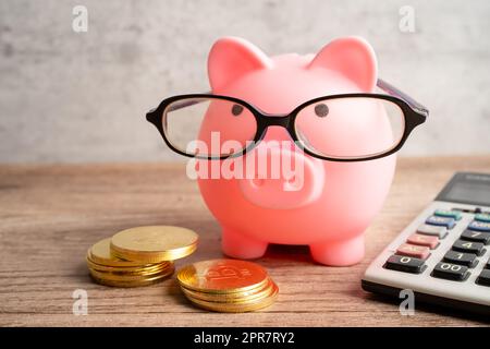 Banco di pigging con occhiali da vista con monete e calcolatrice per risparmiare il concetto di educazione bancaria. Foto Stock