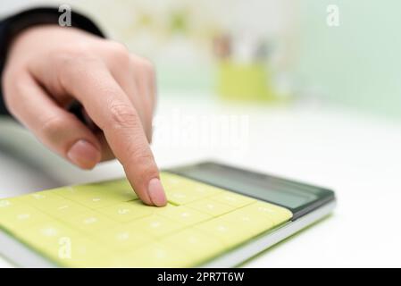 Donna d'affari che punta sulla calcolatrice sulla scrivania con notebook. Donna che preme sul fondo del tavolo con blocco note. Executive Visualizza informazioni recenti. Foto Stock