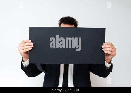 Businessman Holding Speech Bubble con messaggi importanti. Uomo in tuta che presenta le informazioni di Cruial sulla mongolfiera di dialogo. Gentleman che mostra gli aggiornamenti recenti su carta. Foto Stock