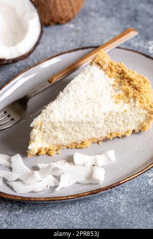 pezzo di cheesecake al cocco su un piatto con cocco fresco Foto Stock