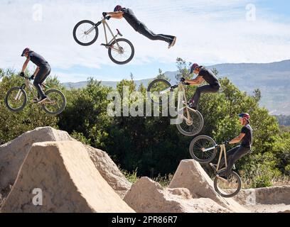 Giovane che mostra le sue abilità ciclistiche mentre è fuori in bicicletta fuori. Gli amanti dell'adrenalina che praticano un salto di sporco all'aperto. Uomo che indossa un casco che fa sport estremi con una bici. Fasi di un salto Foto Stock