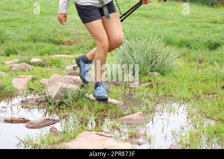 Le gambe degli escursionisti attraversano il fiume in montagna Foto Stock