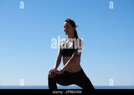 Limbering in su. Scatto di una giovane atleta attraente che si esercita all'aperto. Foto Stock