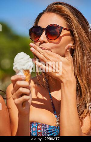 Devi trattarti. Scatto di una bella giovane donna godendo di un cono gelato. Foto Stock