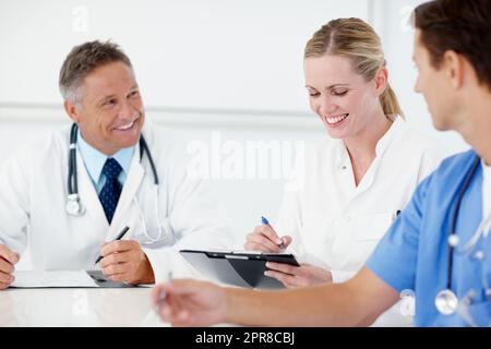 La sua base buona da toccare con voi ragazzi. Tre professionisti medici che hanno un incontro di catch up insieme. Foto Stock