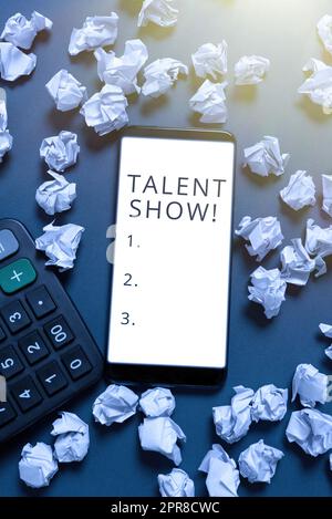 Talent Show di testo per la scrittura a mano. Panoramica aziendale Concorso di animatori proietta le loro prestazioni schermo del telefono con nuova idea su IT circondato da impacchi di carta e calcolatrice Foto Stock