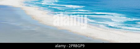 Copiate lo spazio sul mare con le calme onde dell'oceano che si gettano sulla spiaggia. Paesaggio tranquillo e idilliaco con un'atmosfera serena sulla costa per una rilassante vacanza estiva o una destinazione di viaggio Foto Stock