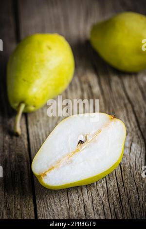 Gruppo di pere verdi su fondo rustico in legno. Frutta fresca e gustosa di stagione Foto Stock