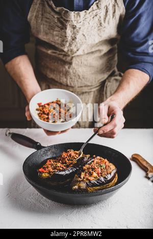 Preparazione delle melanzane ripiene di manzo macinato, pomodori e spezie Foto Stock