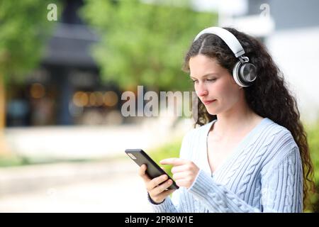 Donna che cammina con telefono e cuffie Foto Stock