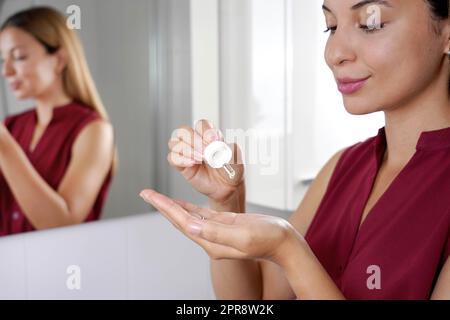 Routine di cura della pelle. Bella donna che tiene una pipetta in mano con siero idratante anti antiossidante invecchiamento. Foto Stock