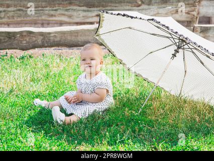 bellissimo bambino in un abito polka-dot è seduto nea ombrello Foto Stock