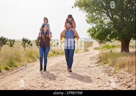 La vita è migliore se trascorsa con la famiglia: Una coppia cammina in fattoria con le due figlie. Foto Stock