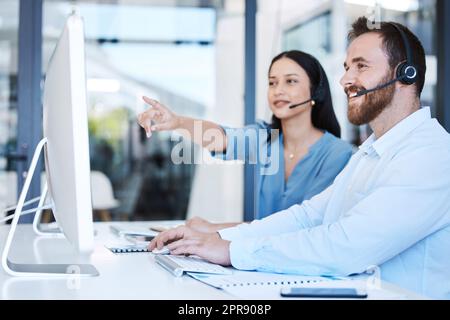 Provare a farlo in questo modo. Due agenti del call center che lavorano insieme su un computer in ufficio. Foto Stock