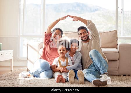 Coppia sorridente con bambini piccoli che creano un tetto simbolico di mani sui loro figli. Sorelle di razza mista protette dai genitori. Madre e padre che coprono le loro figlie con cure familiari e assicurazioni Foto Stock