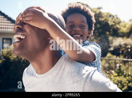 Ritratto di un felice afro-americano che si lega con il suo piccolo bambino fuori. Due maschi neri padre e figlio sembrano felici e positivi mentre sono affezionati e giocano in un cortile Foto Stock