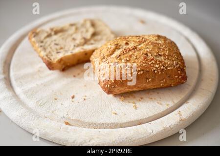 Pane integrale a fette con semi. Fette di pane fatte in casa o rotoli su un tagliere di legno, serviti come un pranzo sano e spuntino per la colazione. Pane integrale o di grano sano e biologico Foto Stock