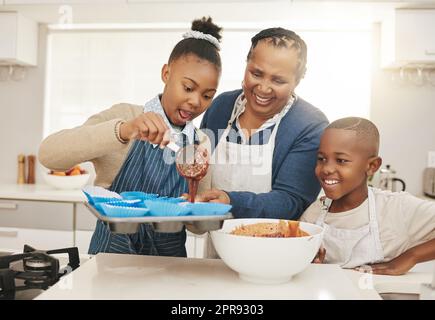 Lascia una stanza, una nonna che cuoce con i suoi due nipoti a casa. Foto Stock