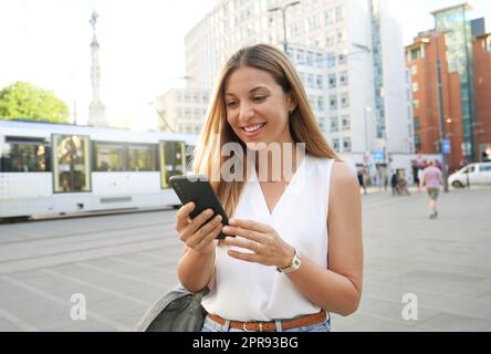 Sorpresa donna d'affari che guarda e texting sul telefono cellulare a piedi in città strada Foto Stock