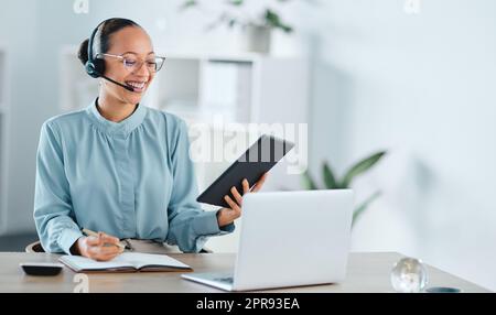 Agente di call center eccitato, felice e allegro che chiama, parla e fa un affare di marketing o una vendita su notebook e tablet. Personale di supporto freelance sorridente, di successo e cordiale multitasking per aiutare i clienti Foto Stock