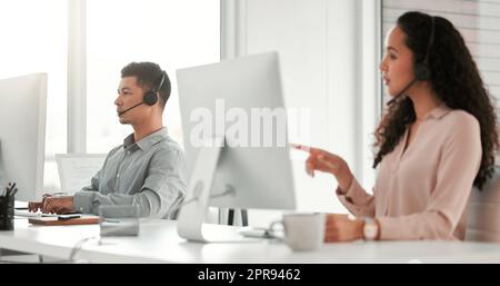 Penso che questo sia ciò di cui avete bisogno: Due giovani operatori di call center che lavorano in un ufficio. Foto Stock