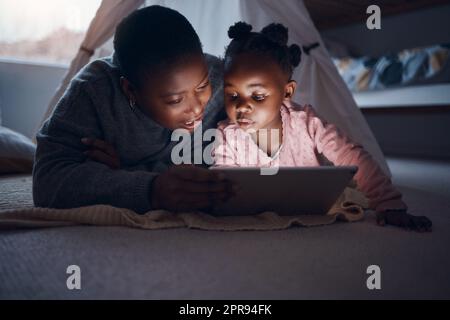 Perché non scegliete una storia: Una madre che legge le storie dell'ora di dormire con sua figlia su un tablet digitale. Foto Stock