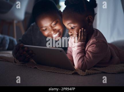 E poi vivevano felicemente. Una madre che leggeva storie sull'ora di dormire con sua figlia su un tablet digitale. Foto Stock