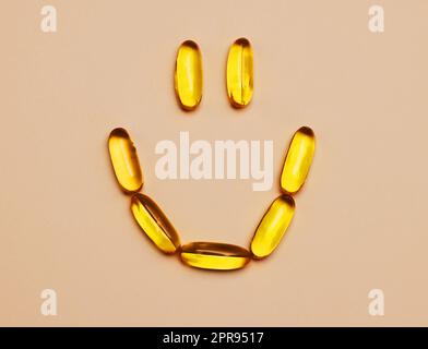 Una pillola per mantenere il sorriso sul viso. Studio shot di pillole che formano un volto sorridente su uno sfondo arancione. Foto Stock