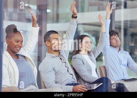Abbiamo tutti delle domande: Un gruppo di uomini d'affari che si alzano le mani durante una riunione sul lavoro. Foto Stock
