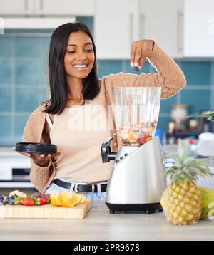 I frullati mi forniscono energia rapida e duratura. Una giovane donna che prepara un frullato sano a casa. Foto Stock